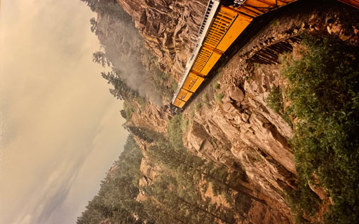 the back of a train traveling along a mountain side