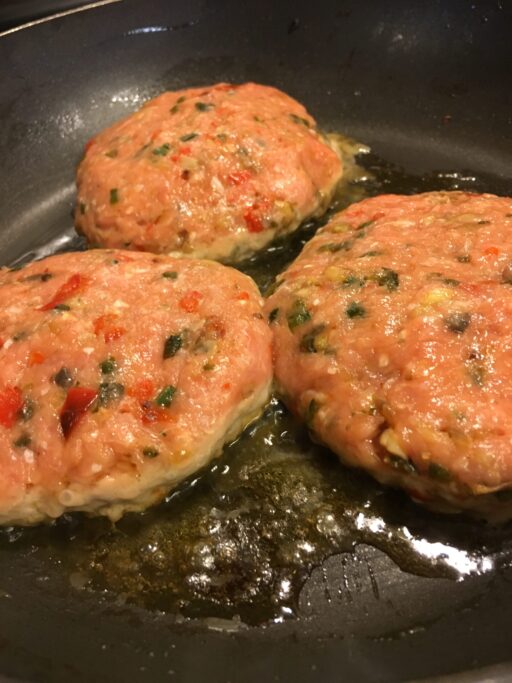 raw turkey burgers cooking in a pan